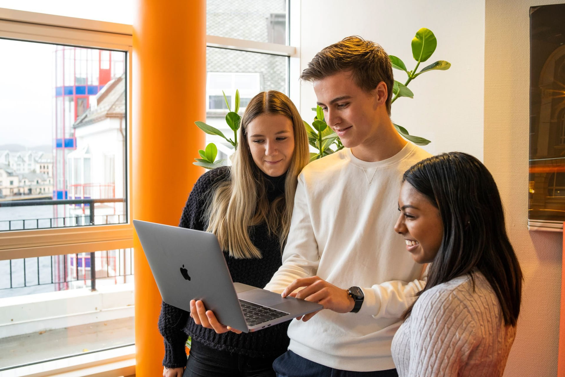 Tre elever på Akademiet kikker på Macbooken