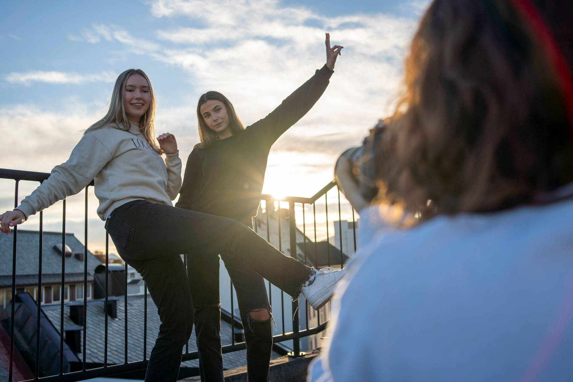 To elever står med sola og utsikt bak seg