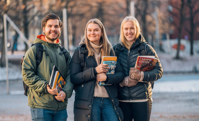 Tre elever ved Akademiet Privatistskole og Nettstudier står utendørs med bøker i hendene
