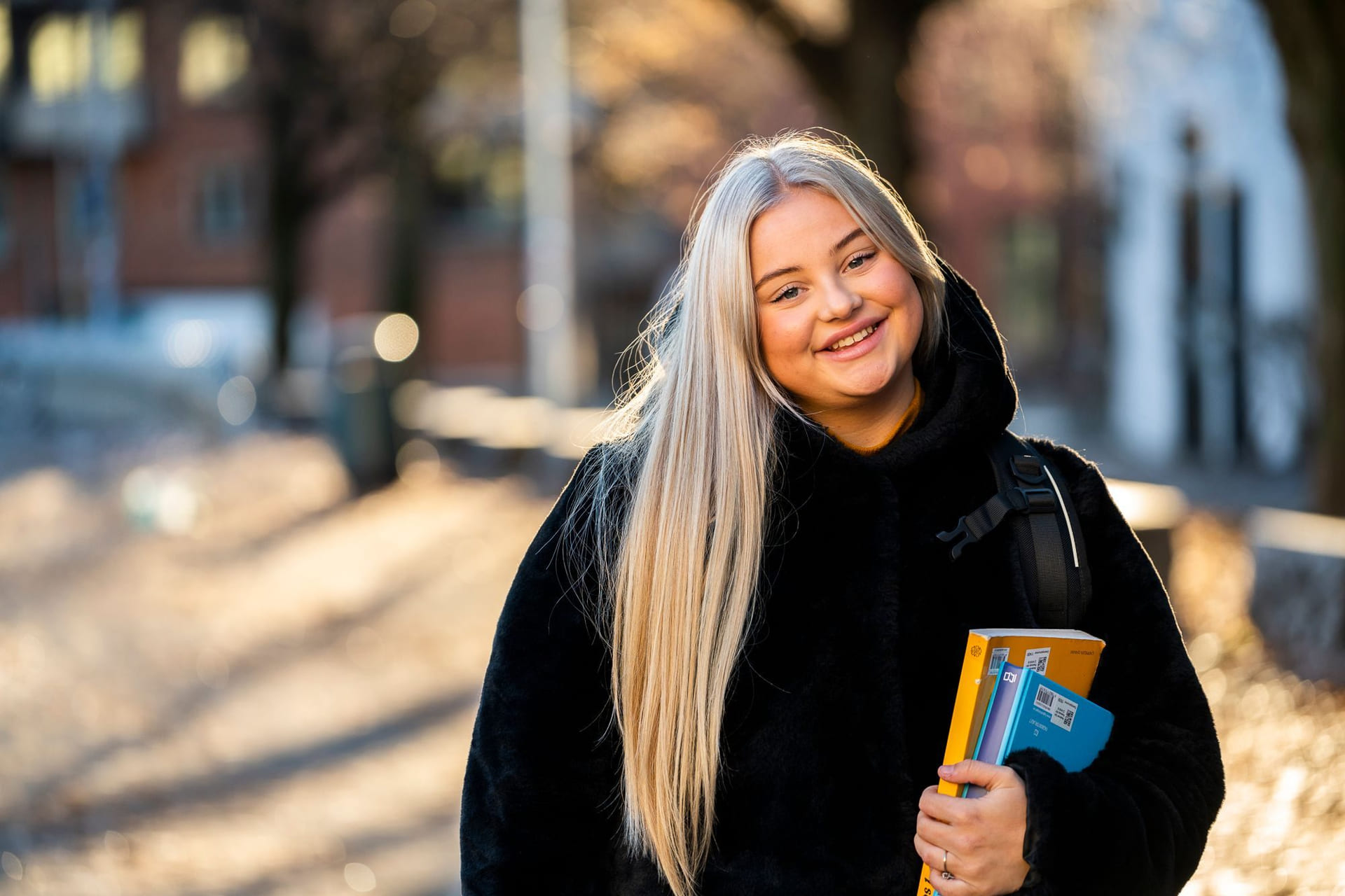 Privatist smiler og holder en lærerbok i hånden