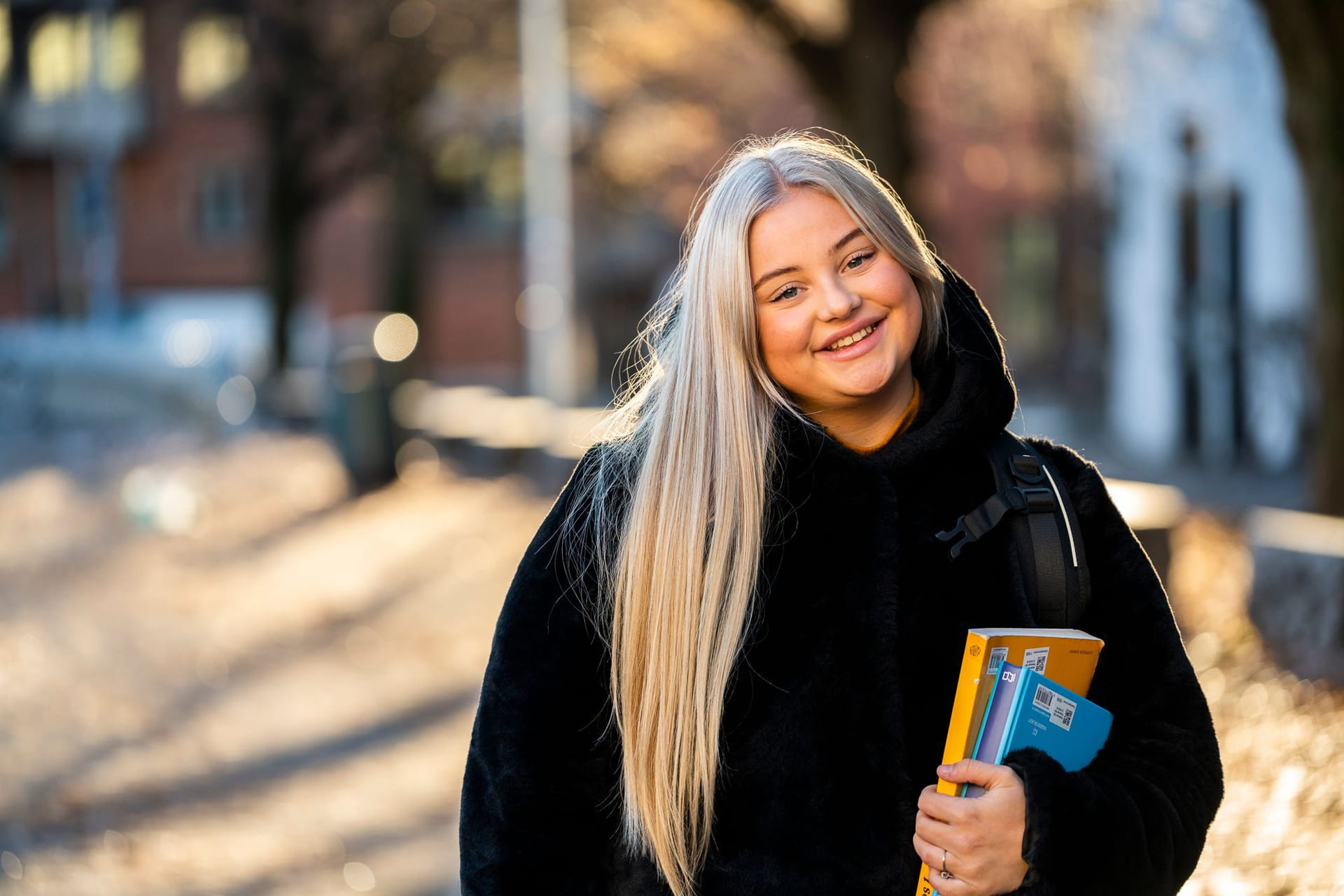 Privatist smiler og holder en lærerbok i hånden