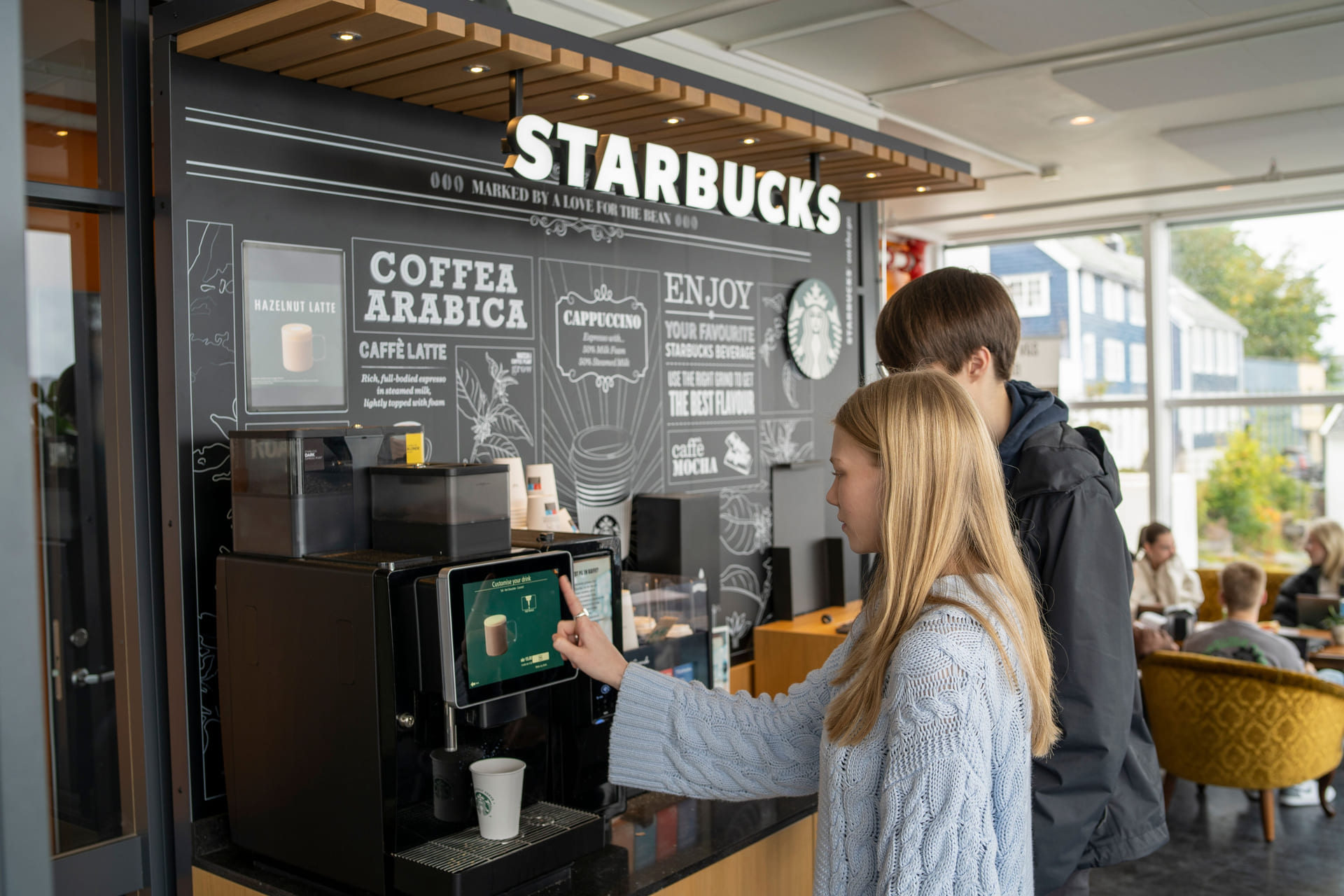 To elever kjøper kaffe fra Starbucks på Akademiet