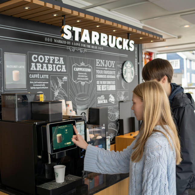 To elever kjøper kaffe fra Starbucks på Akademiet