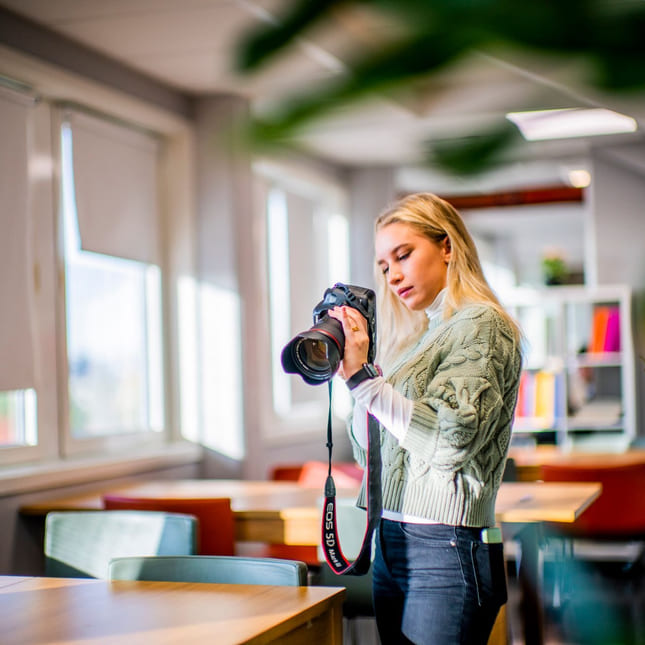 Elev på Medier og kommunikasjon tar bilder med fotokamera