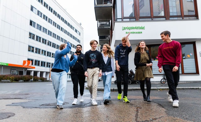 Elever på Akademiet går utenfor skolen med medelever og smiler