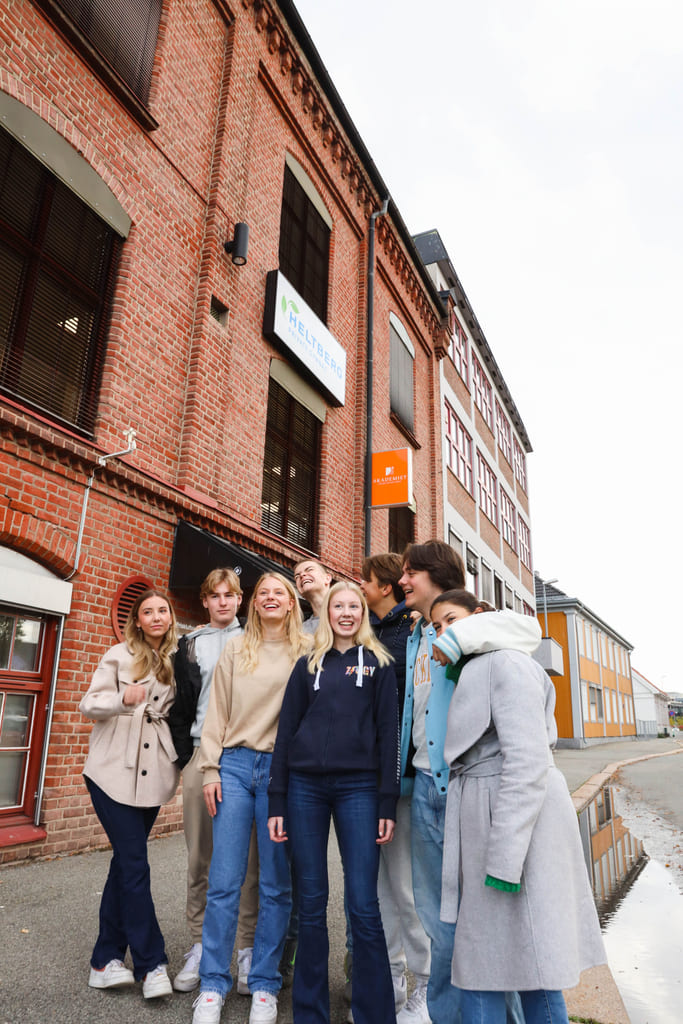 Elever på Akademiet VGS Heltberg Drammen står utenfor inngangen på skolen.