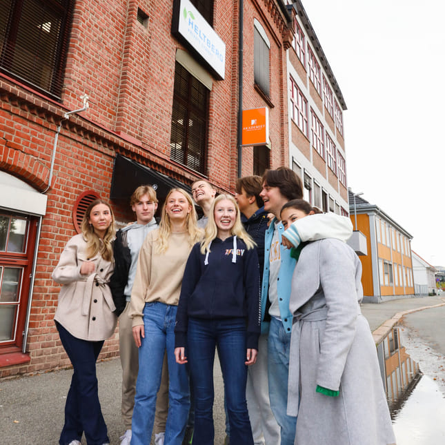 Elever på Akademiet VGS Heltberg Drammen står utenfor inngangen på skolen.