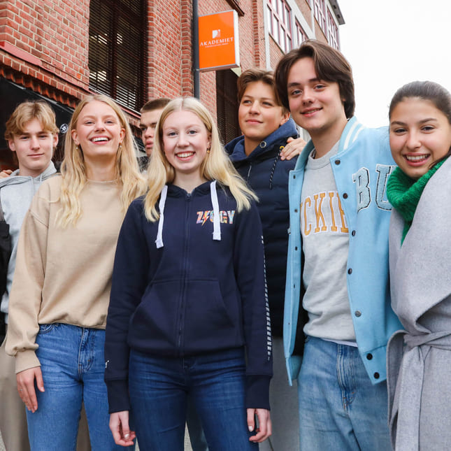 Elever på Akademiet VGS Heltberg Drammen står utenfor inngangen på skolen.