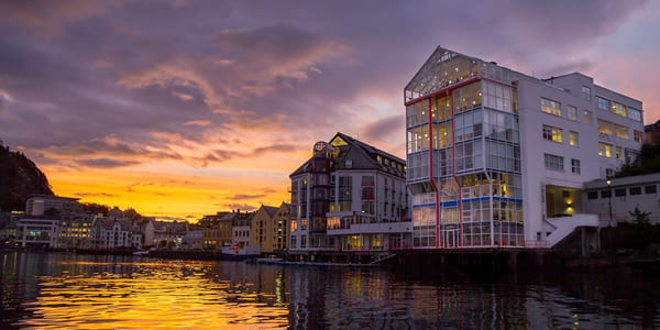 Akademiet VGS Ålesund hvor bygget sees ved vannkanten og i solnedgang