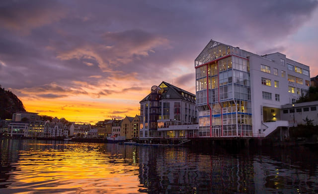 Akademiet VGS Ålesund hvor bygget sees ved vannkanten og i solnedgang