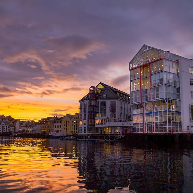 Akademiet VGS Ålesund hvor bygget sees ved vannkanten og i solnedgang