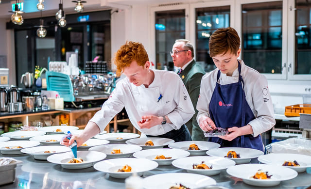 Elever på Akademiet Norsk Restaurantskole tilbereder retter til servering