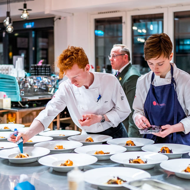 Elever på Akademiet Norsk Restaurantskole tilbereder retter til servering