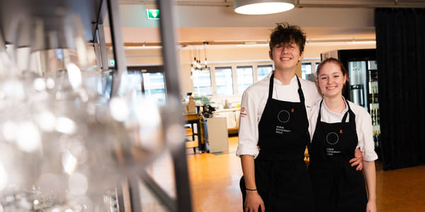 Elever på Akademiet Norsk Restaurantskole smiler med forkler på