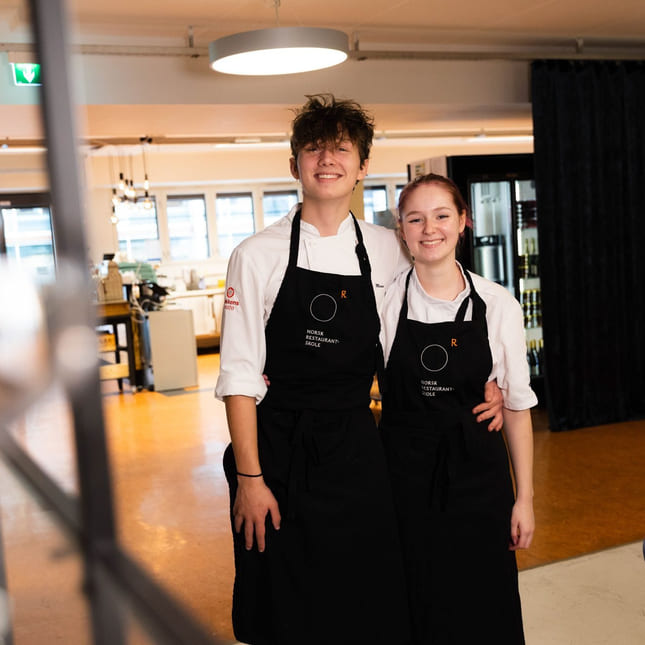 Elever på Akademiet Norsk Restaurantskole smiler med forkler på
