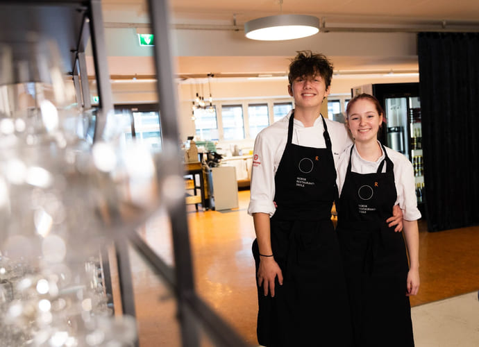 Elever på Akademiet Norsk Restaurantskole smiler med forkler på