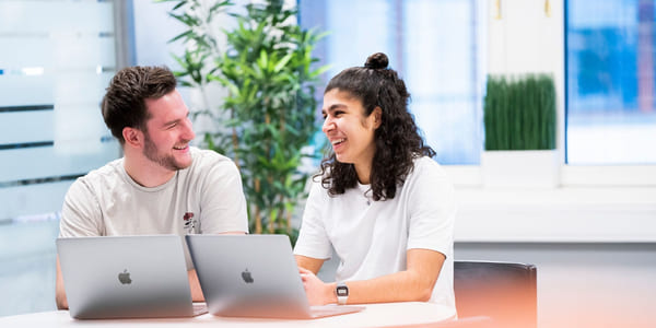 To privatister fra Akademiet Privatistskole sitter ved et bord og jobber med en MacBook