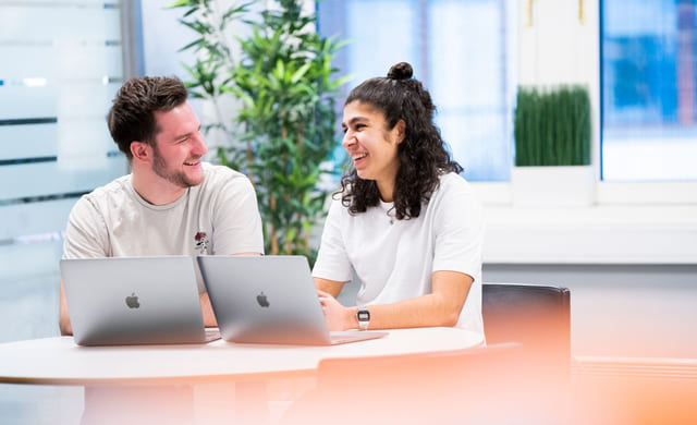 To privatister fra Akademiet Privatistskole sitter ved et bord og jobber med en MacBook