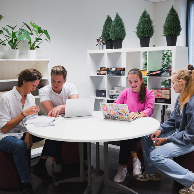 Fire elever på Akademiet i Sandvika jobber fokusert rundt et bord på skolen