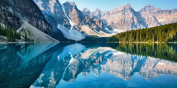 Bilde av høye fjell i Canada som speiler seg i en blank innsjø
