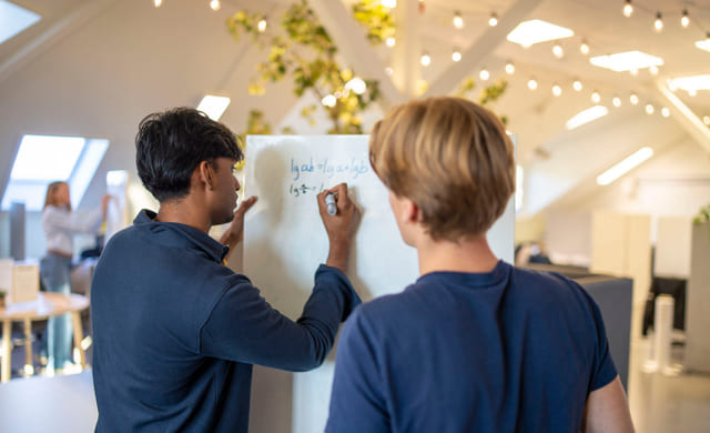 Elever og mentor jobber med fag på tavle.