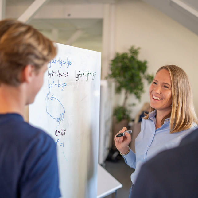 Elever og mentor jobber med fag på tavle.