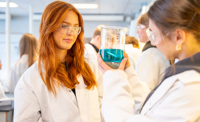 To elever på Akademiet VGS Drammen har på labfrakk og undersøker reagensrør i kjemitime