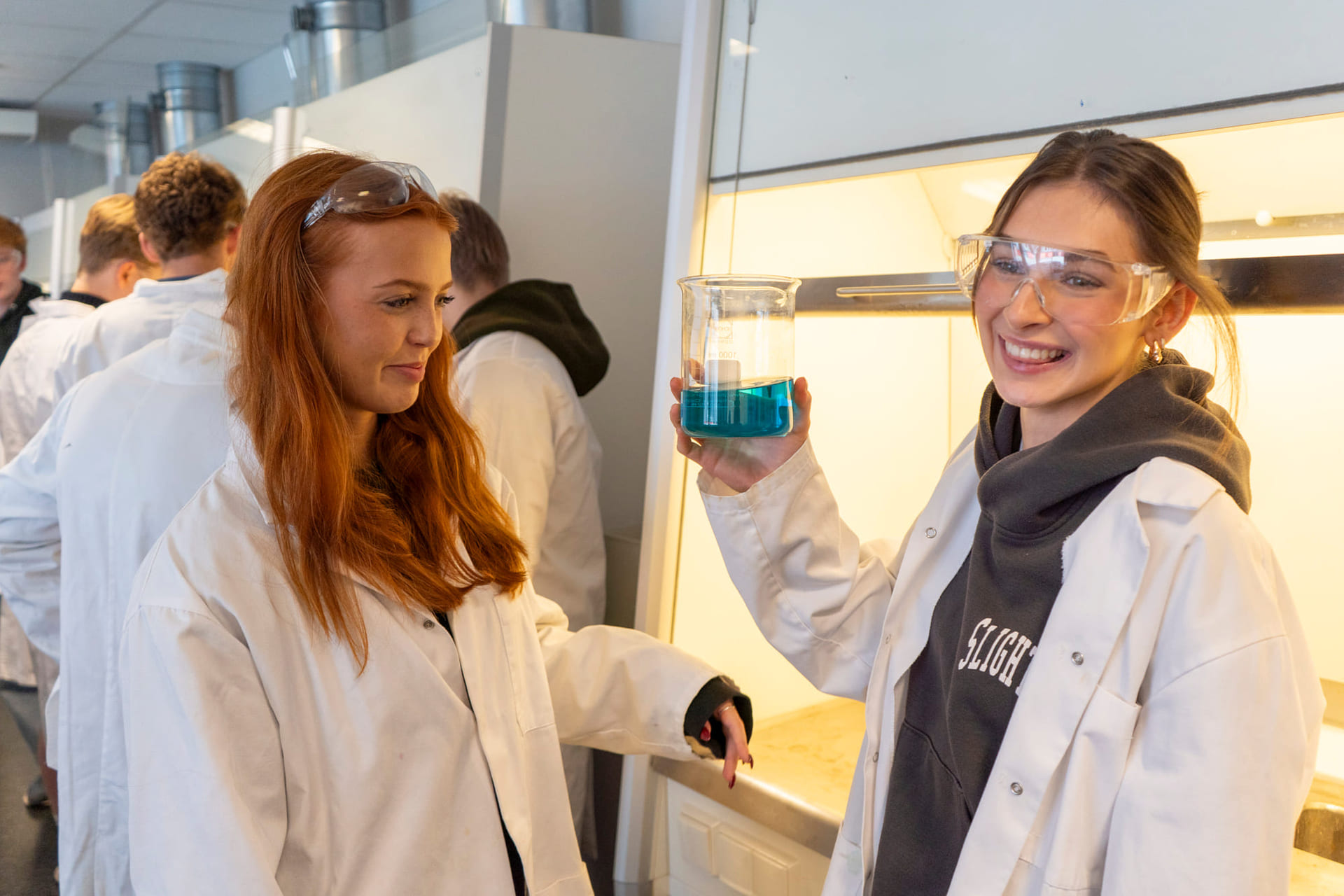 To elever på Akademiet VGS Drammen har på labfrakk og undersøker reagensrør i kjemitime