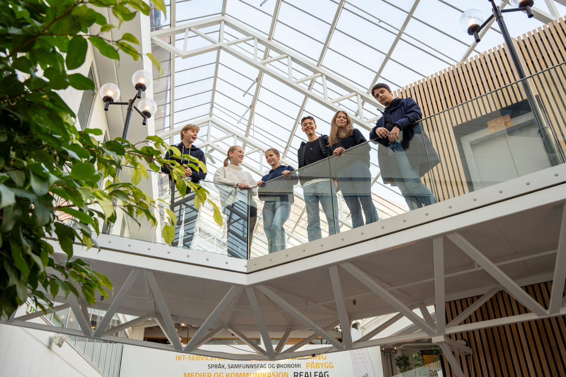 Elever står på en innendørs bro på Akademiet VGS Sandnes