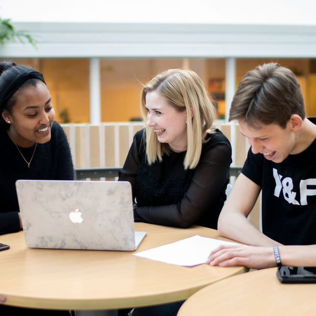 Elev og en lærer sitter med en Macbook på Akademiet VGS Sandnes