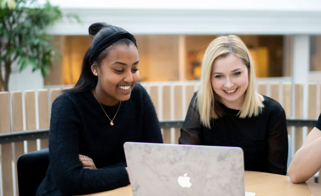 Elev og en lærer sitter med en Macbook på Akademiet VGS Sandnes