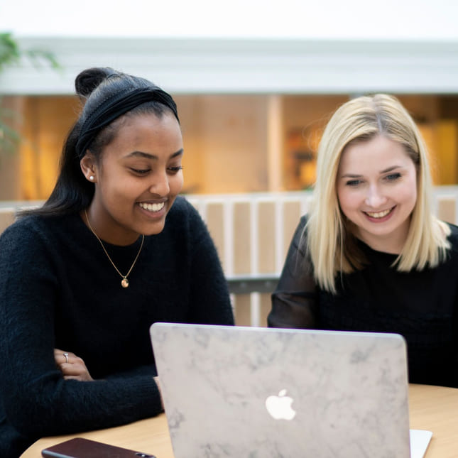 Elev og en lærer sitter med en Macbook på Akademiet VGS Sandnes