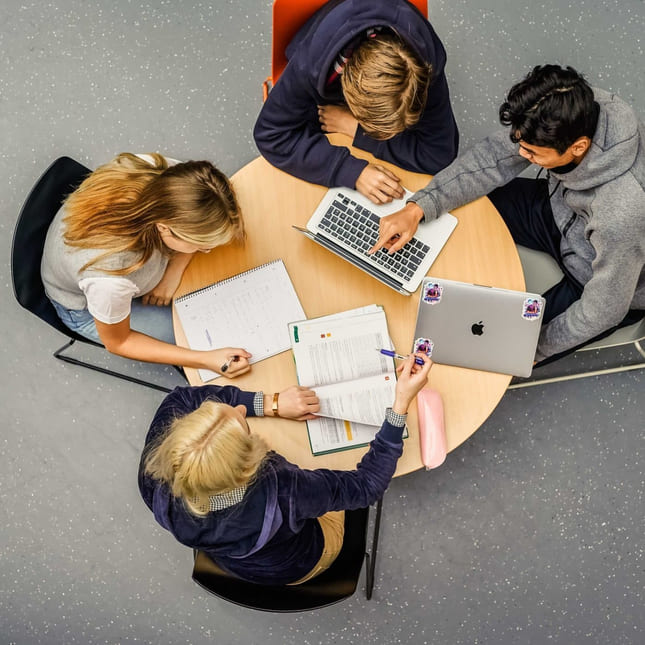 Privatister sitter rundt et bord og jobber med skolefag på Akademiet