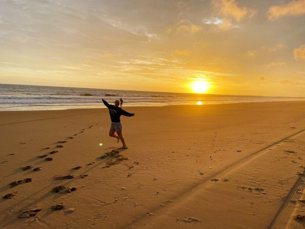 Person som hopper på en strand i solnedgang