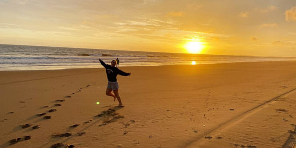 Person som hopper på en strand i solnedgang