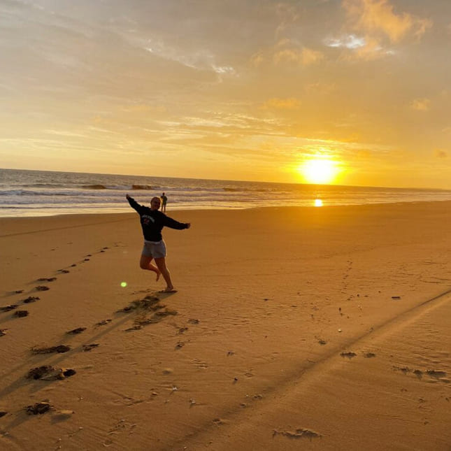 Person som hopper på en strand i solnedgang