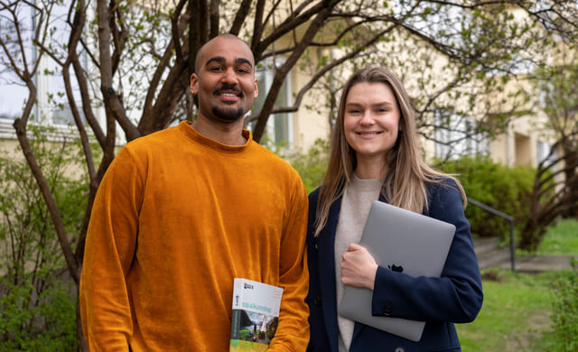 To elever smiler utenfor Akademiet Privatistskole med bok og macbook.