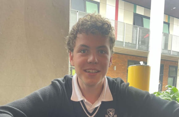 Fredrik smiler mot kamera i skoleuniform i New Zealand.
