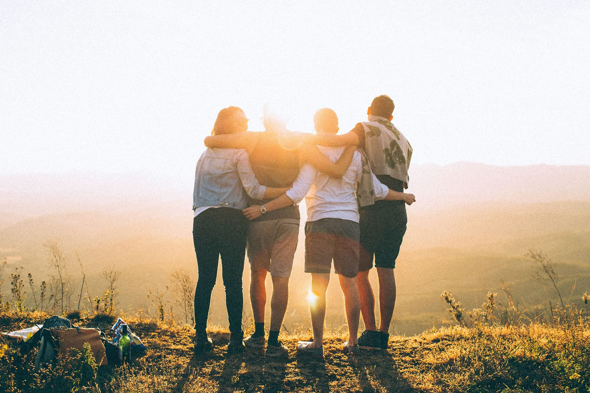 Fire elever står på en åskam og ser mot sola
