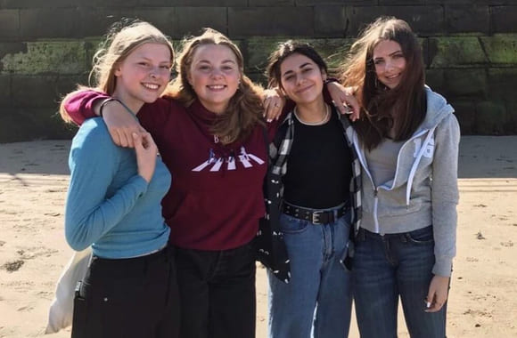 Fire elever smiler på en strand i England