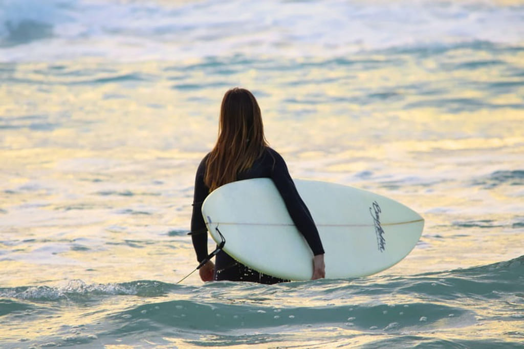 Jente med surfebrett i vannet