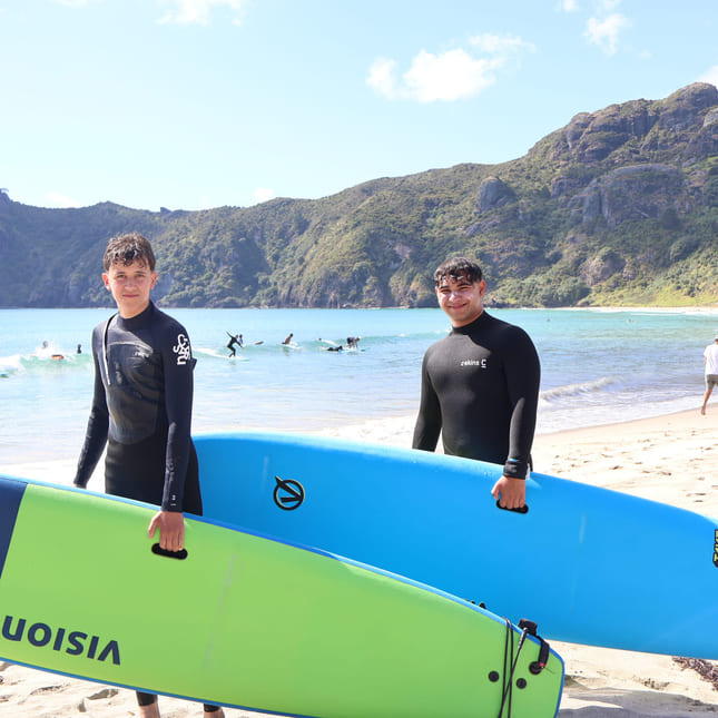 Elever har surfekurs på stranden i new zealand.