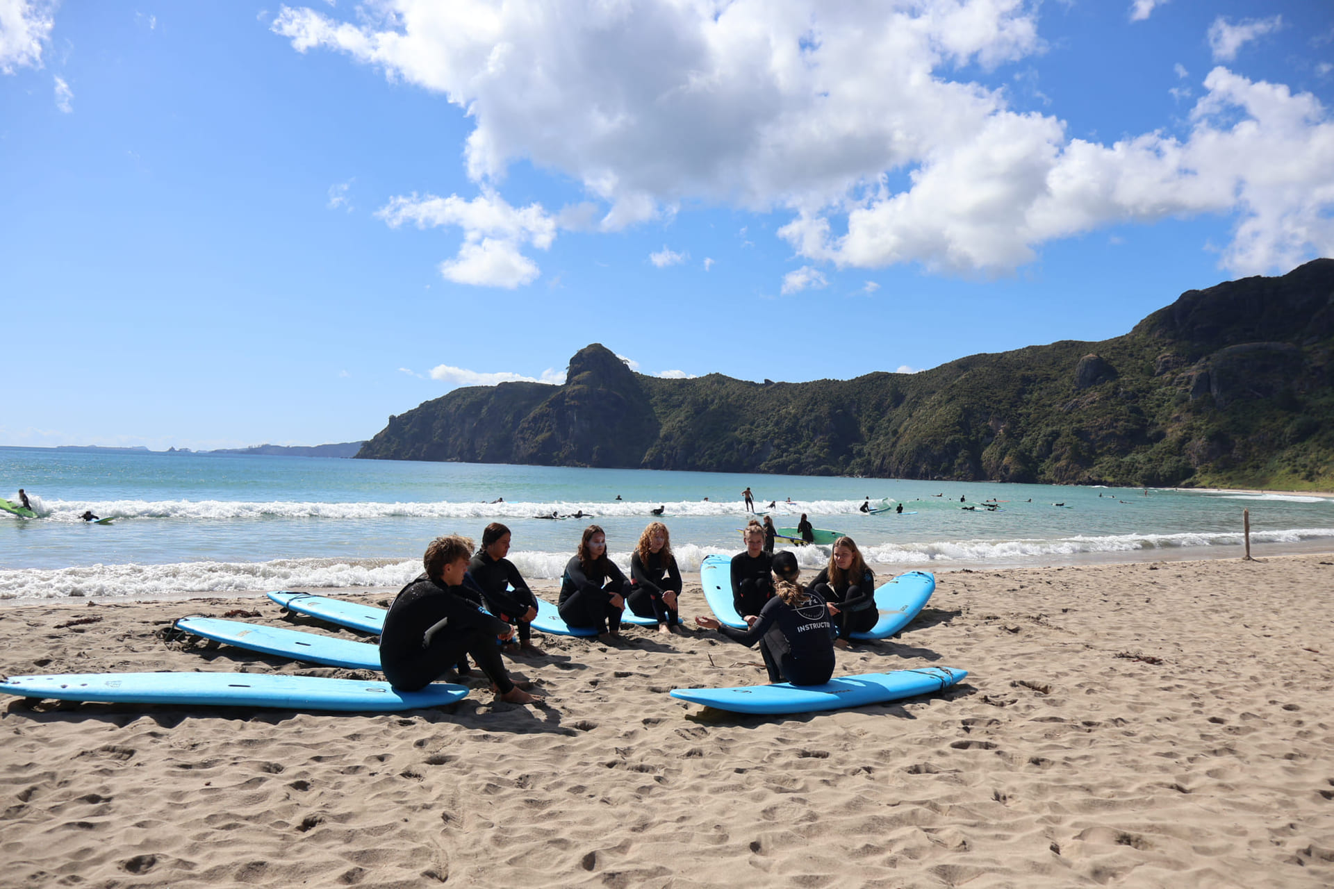 Elever har surfekurs på stranden i new zealand.