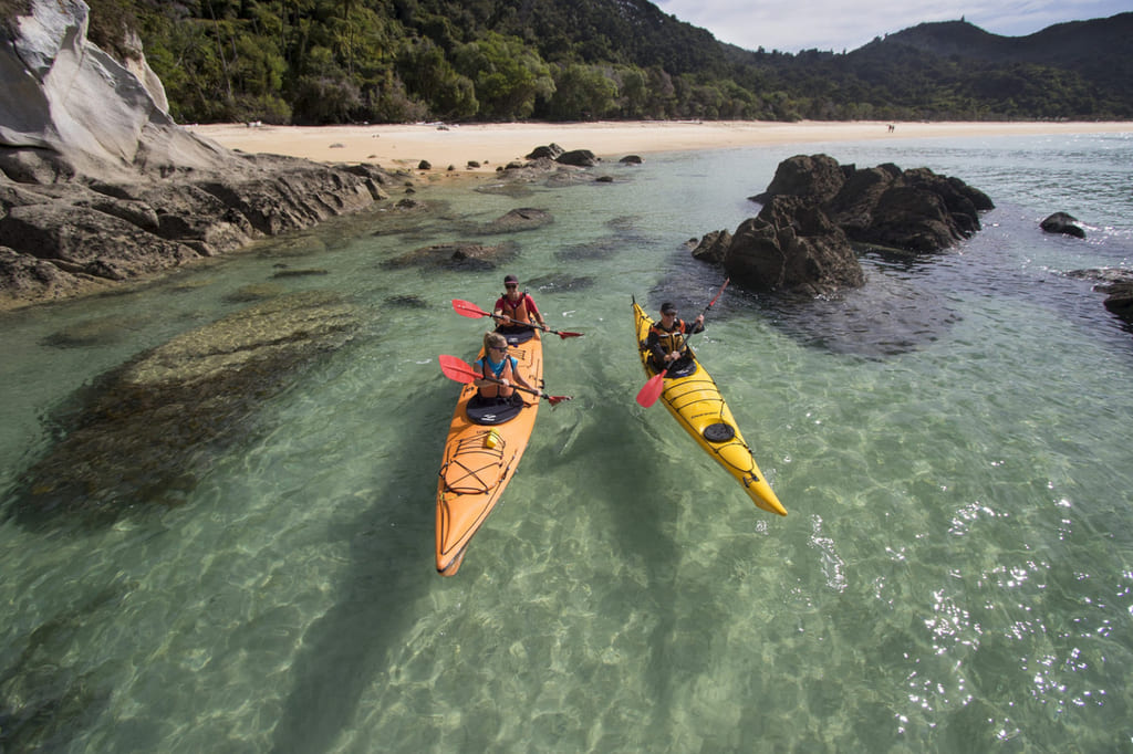 Tre kajakker på en strand i new zealand.