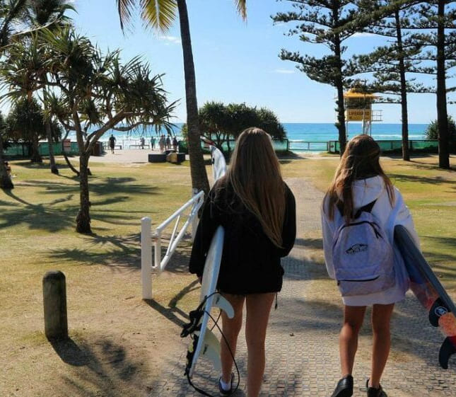 Elever med surfebrett under armene på vei til stranden i Australia