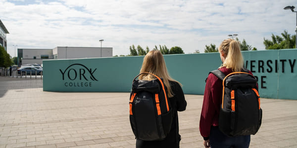 To personer står utenfor York College med Akademietsekker.