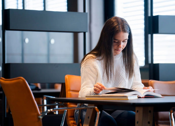 Jente leser en bok på Akademiet