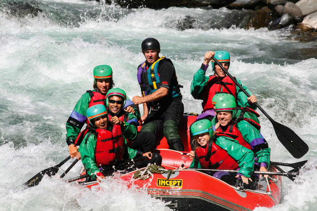 Flere folk sitter i en båt på rafting nedover en elv i Canada