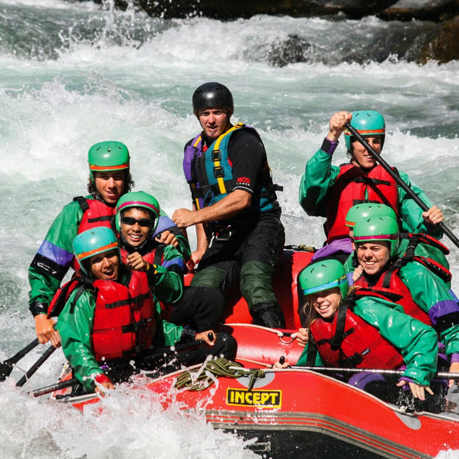 Flere folk sitter i en båt på rafting nedover en elv i Canada