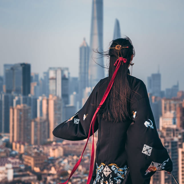 Dame ser utover en kinesisk by iført tradisjonell kinesisk kostyme